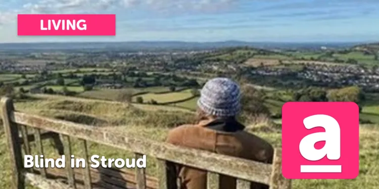 A person sits on a bench on the hills above Stroud. The person has their back to us and is wearing a brown jacket and a greyish beanie hat